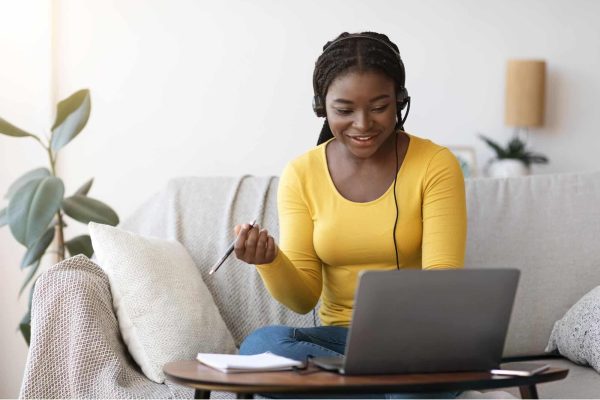 Webinars Young woman sitting on a sofa attending a webinar.